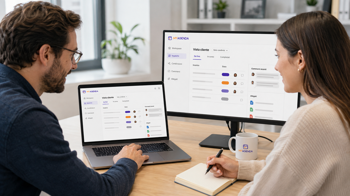 Due colleghi confrontano su laptop e monitor la vista cliente di myAgenda, con incarichi condivisi, stato di avanzamento e commenti.